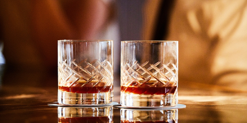Two crystal glasses of whiskey on a bar counter, celebrating Irish Heritage Month at Doyle’s Tasting Tuesdays. Each week features a different Irish spirit brand for an exclusive tasting experience. 