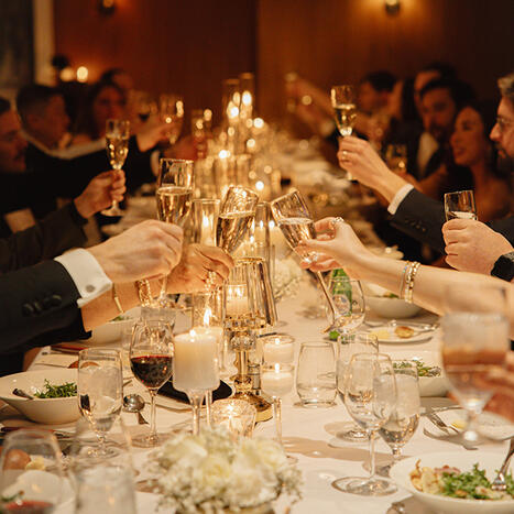 Glover Park wedding reception: Guests seated at a long banquet table, and toasting with champagne glasses