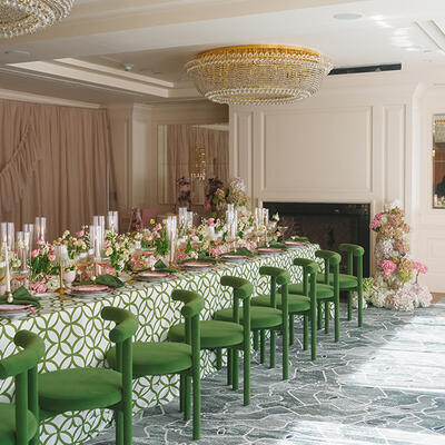 A wedding reception setup at Foxhall featuring a vibrant pink and green color palette with coordinated table accents and elegant green chairs