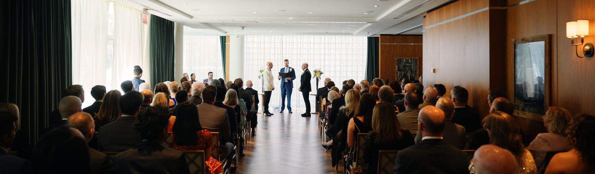 Room set up for a wedding ceremony with guests present as the couple exchange their vows.