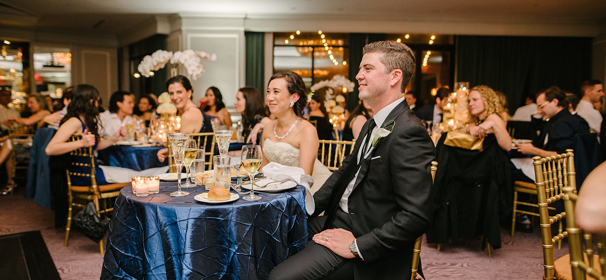 Wedding guests sitting at at table covered in a blue tablecloth