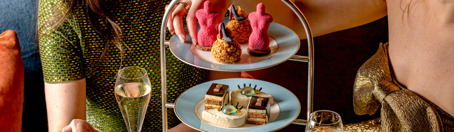 Two women enjoying a Schiaparelli-inspired Afternoon Tea at The Kensington hotel in London, featuring artistic pastries and Champagne near the V&A museum