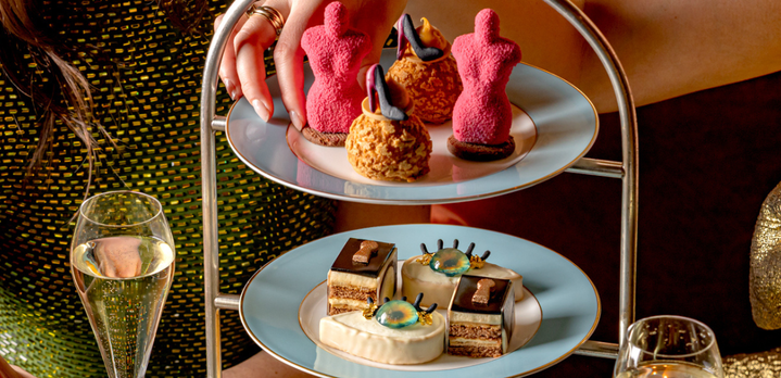 Two women enjoying a Schiaparelli-inspired Afternoon Tea at The Kensington hotel in London, featuring artistic pastries and Champagne near the V&A museum