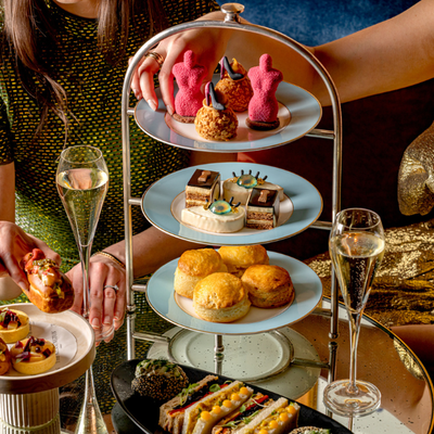 Two women enjoying a Schiaparelli-inspired Afternoon Tea at The Kensington hotel in London, featuring artistic pastries and Champagne near the V&A museum