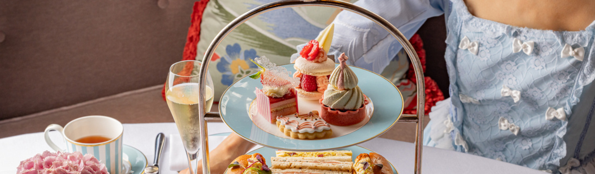 A woman enjoys a delicious afternoon tea in a bright, elegant room at The Kensington Hotel.