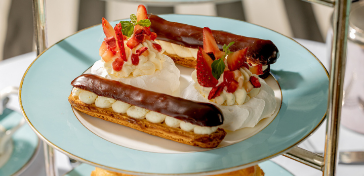 Close-up shot of an afternoon tea plate featuring freshly baked choux pastry éclairs at The Kensington