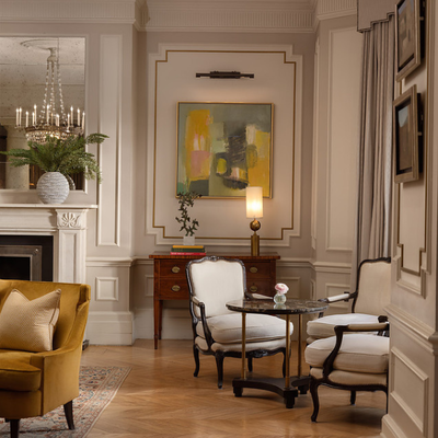 An intimate dinner setting for two featuring two light grey armchairs and a small table in The Drawing Room at The Kensington Hotel