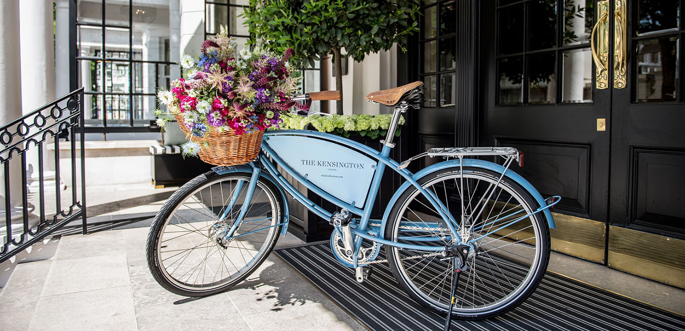 light blue Pashley bike with basket filled with flowers parked at the hotel entrance