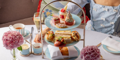 A guest at The Kensington Hotel enjoying afternoon tea, with a tiered stand of pastries and a cup of tea in an elegant setting as part of V&A Experience offer.