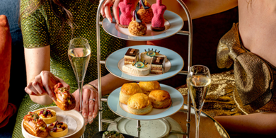 Ladies enjoying afternoon tea at The Kensington Hotel, with a tiered stand of pastries and a cup of tea in an elegant setting, as part of the V&A Experience offer.