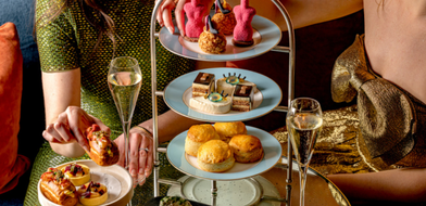 Ladies enjoying afternoon tea at The Kensington Hotel, with a tiered stand of pastries and a cup of tea in an elegant setting, as part of the V&A Experience offer.