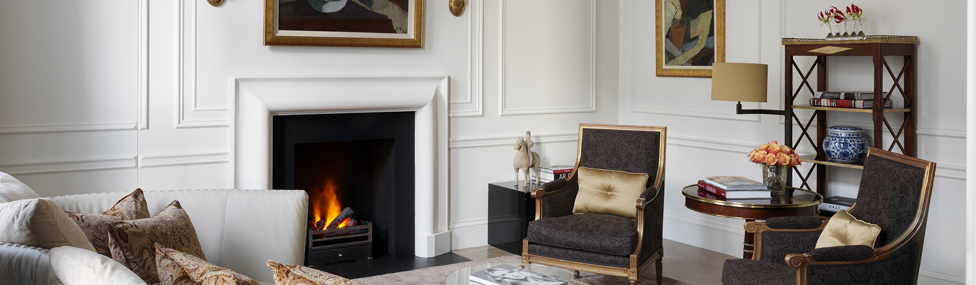 The Kensington Hotel's luxurious Suite. A spacious living area with a sofa, armchairs, and fireplace, perfect for a winter escape.