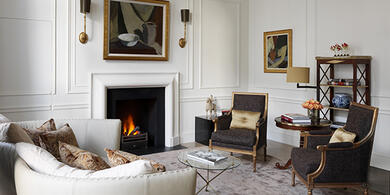 The Kensington Hotel's luxurious Suite. A spacious living area with a sofa, armchairs, and fireplace, perfect for a winter escape.