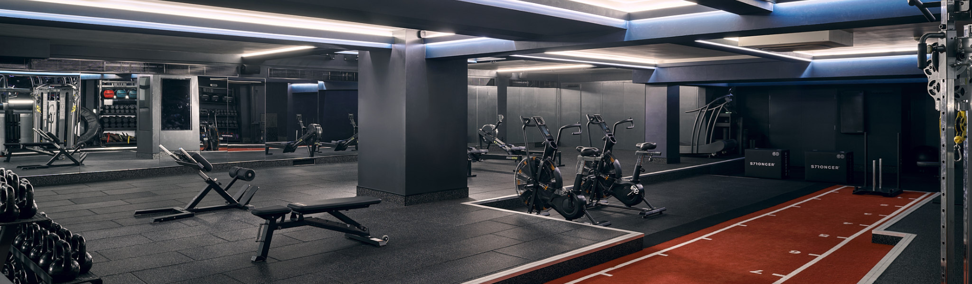 A clean and organized gym The Third Space with rows of neatly arranged dumbbells and two stationary bicycles.