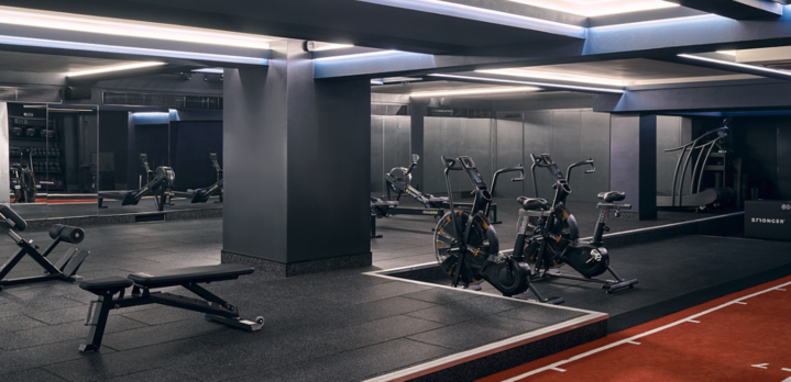 A clean and organized gym The Third Space with rows of neatly arranged dumbbells and two stationary bicycles.
