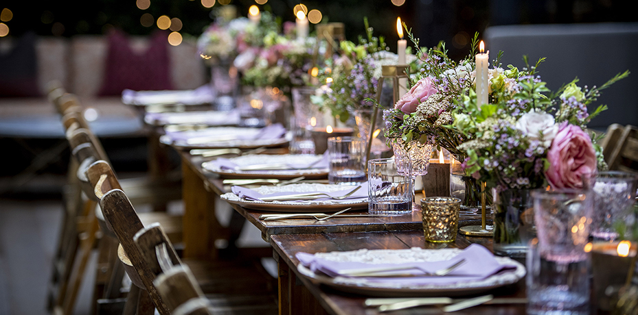 An elegant long dining table at The Marylebone, perfectly set for a private event with lush pink and green floral arrangements and sophisticated ambient lighting