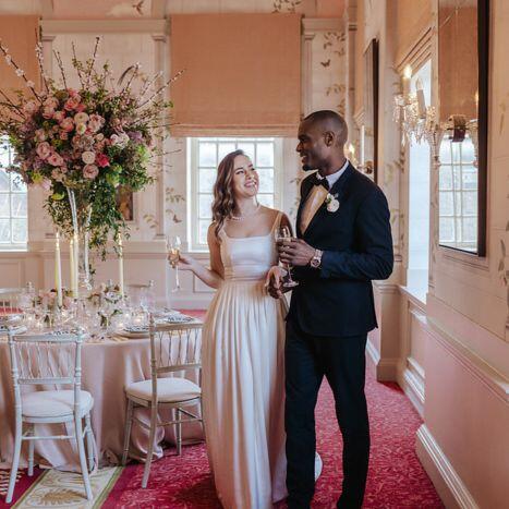 A bride and groom share a joyful look as they admire their grand reception at Queen Mary Hall, featuring candlelit tables and refined floral decor.