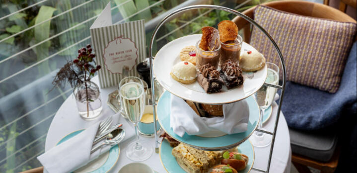 View from above of a three-tier stand of desserts at The River Lee afternoon tea, surrounded by tea cups and champagne .