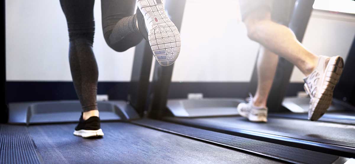 closeup of two people running on treadmill