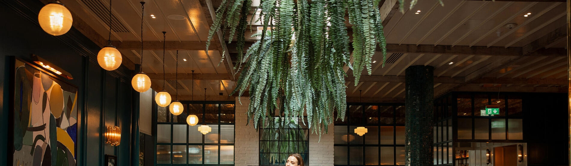Louise O'Neill walking in the vibrant interior of The Grill Room restaurant during her curated weekend getaway at The River Lee in Cork.