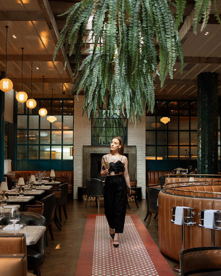 Louise O'Neill walking in the vibrant interior of The Grill Room restaurant during her curated weekend getaway at The River Lee in Cork.