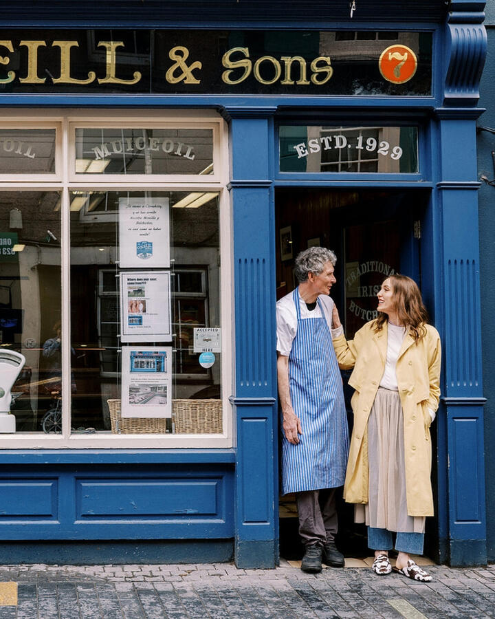 Louise O'Neill smiling with her father in front of a blue-fronted butcher shop in Cork.