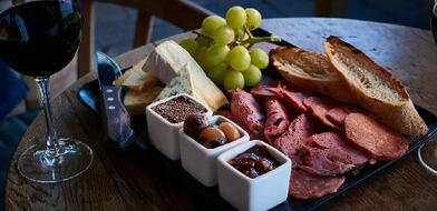 Sharing board with a selection of meat, cheese and bread and a glass of red wine