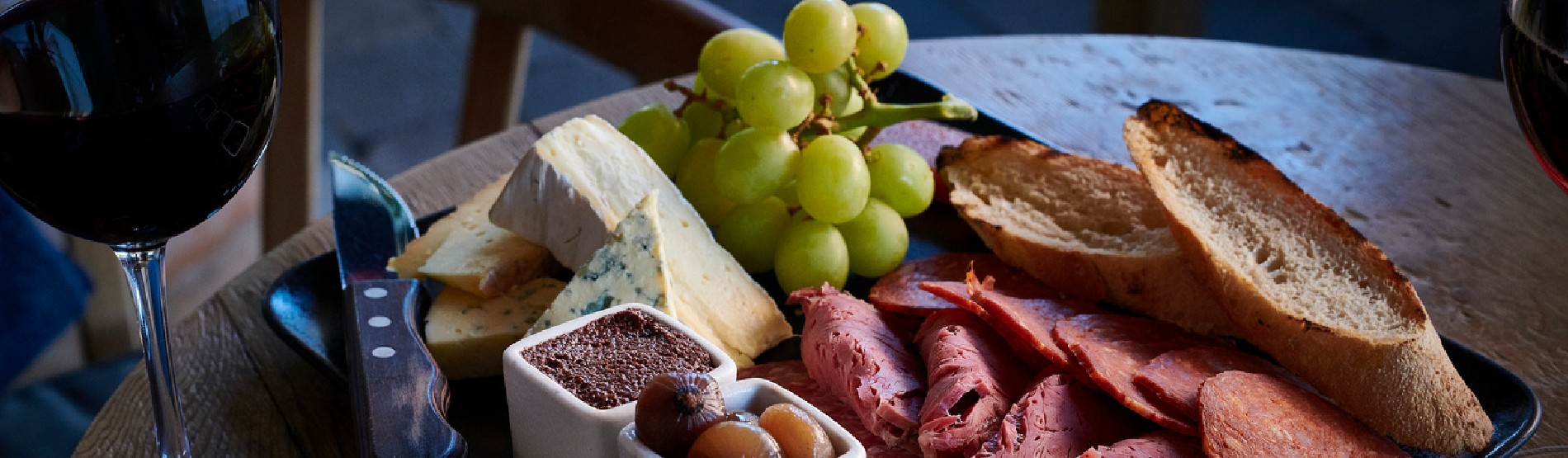 Sharing board with a selection of meat, cheese and bread and a glass of red wine
