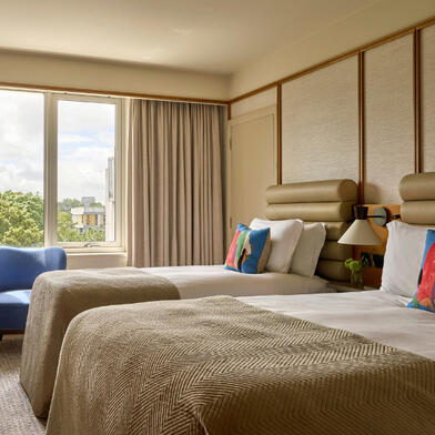 A Deluxe King River View room at The River Lee Hotel, showcasing a spacious king bed and a seating area with two signature blue armchairs