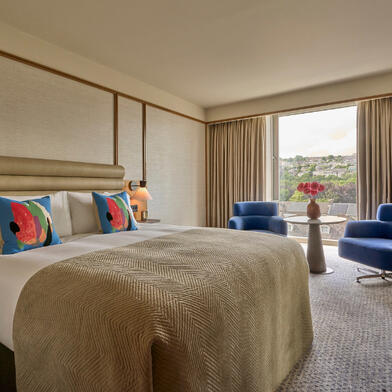 Deluxe Room with a river view at The River Lee Hotel, featuring a large king bed and two signature blue armchairs