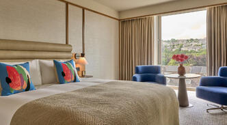 Deluxe Room with a river view at The River Lee Hotel, featuring a large king bed and two signature blue armchairs