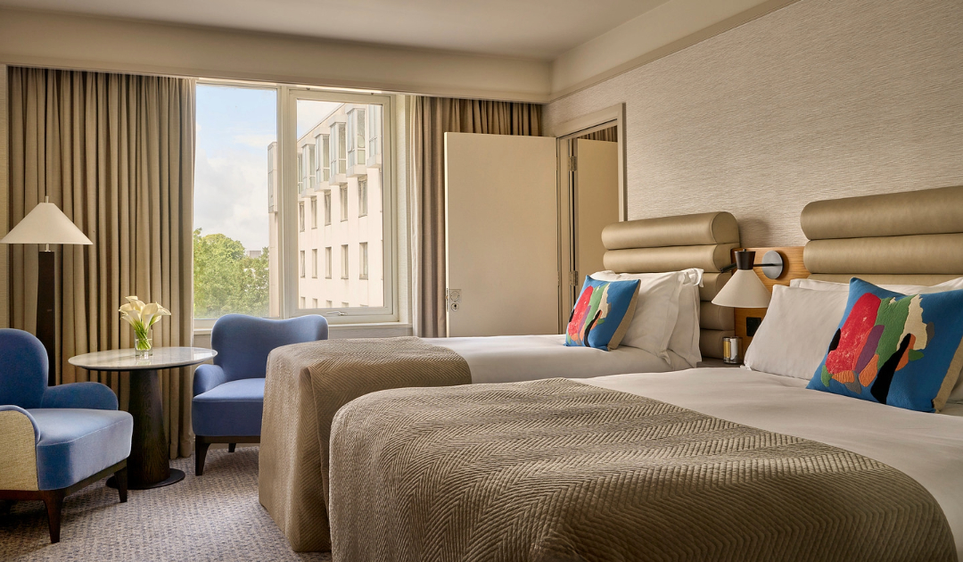 Classic Room with a double and single bed, featuring two blue armchairs in front of the window at The River Lee Hotel ideal for a family or group stay.