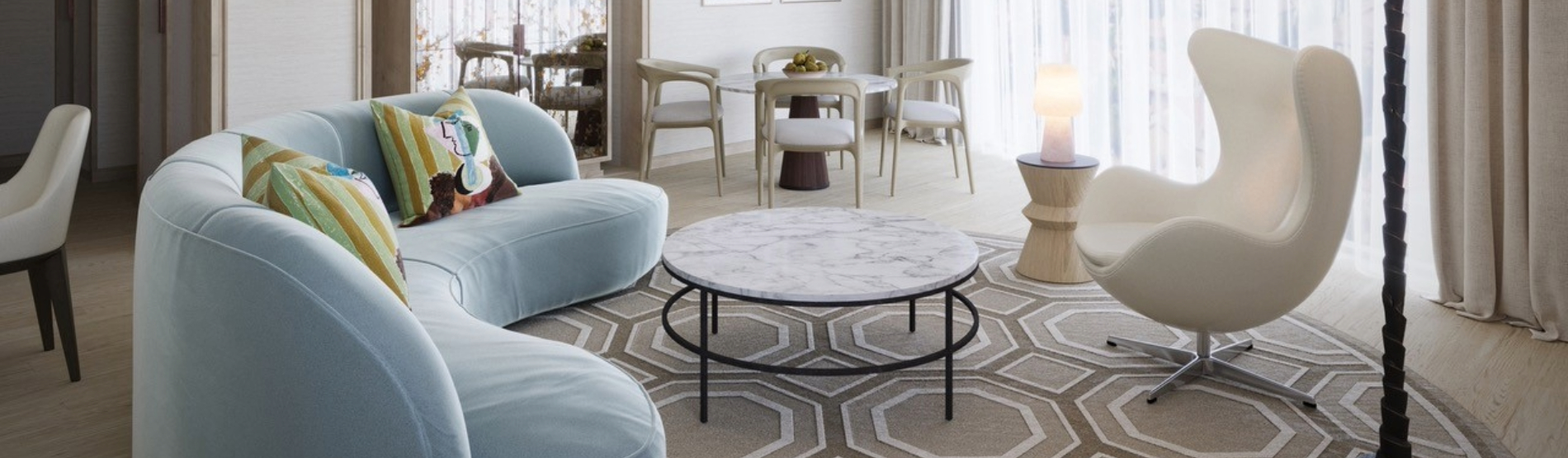 llustrative view of the Luxury Suite seating area at The River Lee, featuring a large sofa bed, armchair, and a 4-person dining table in a bright, sunlit room