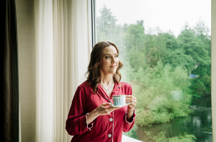 Louise enjoys a quiet suite moment at The River Lee hotel, sipping coffee by the window in a red pyjama set as the city wakes up outside.