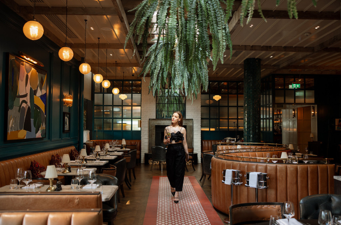 Louise walks into The River Club in Cork, arriving for a relaxed dinner with friends in a stylish restaurant setting.