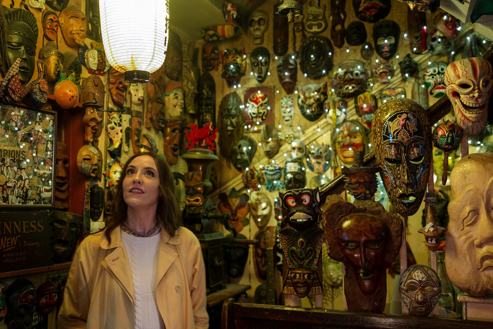 Louise sits in a Cork pub, gazing at the iconic walls lined with posters and memorabilia, soaking in the atmosphere.