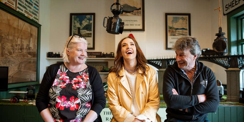 Louise enjoys a relaxed moment in a pub, laughing with a woman and a man seated beside her.