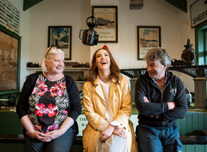 Louise enjoys a relaxed moment in a pub, laughing with a woman and a man seated beside her.