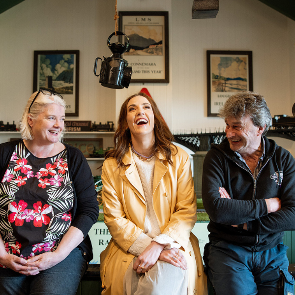 Louise enjoys a relaxed moment in a pub, laughing with a woman and a man seated beside her.
