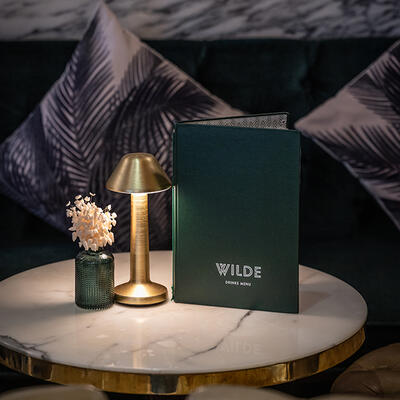 An intimate table for two at WILDE, elegantly set, glowing under soft lighting for a romantic dining experience.