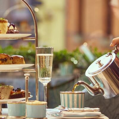 Elegant afternoon tea setting at The Galery, with a champagne flute and a tiered stand filled with various pastries and sandwiches while tea is being served.