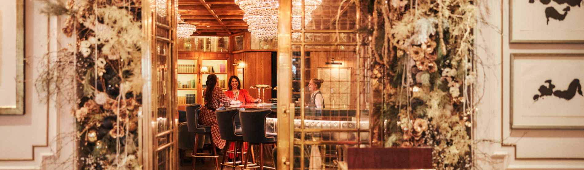 Two ladies celebrating Christmas at The Kensington hotel, enjoying drinks and laughter at the bar.