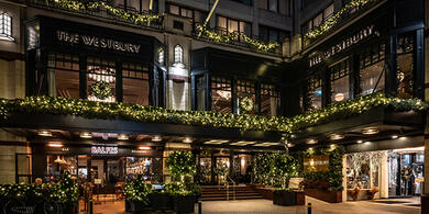 The exterior view of The Westbury hotel at night, adorned with festive Christmas lights and wreaths on the windows.