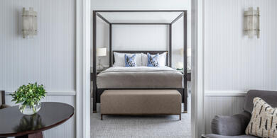 Luxury Signature Suite at The Westbury Dublin, showing a four-poster bed and private lounge area with a armchair. 