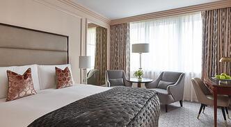 Sun-drenched classic king room at The Westbury Hotel, showcasing a king bed and twin armchairs.