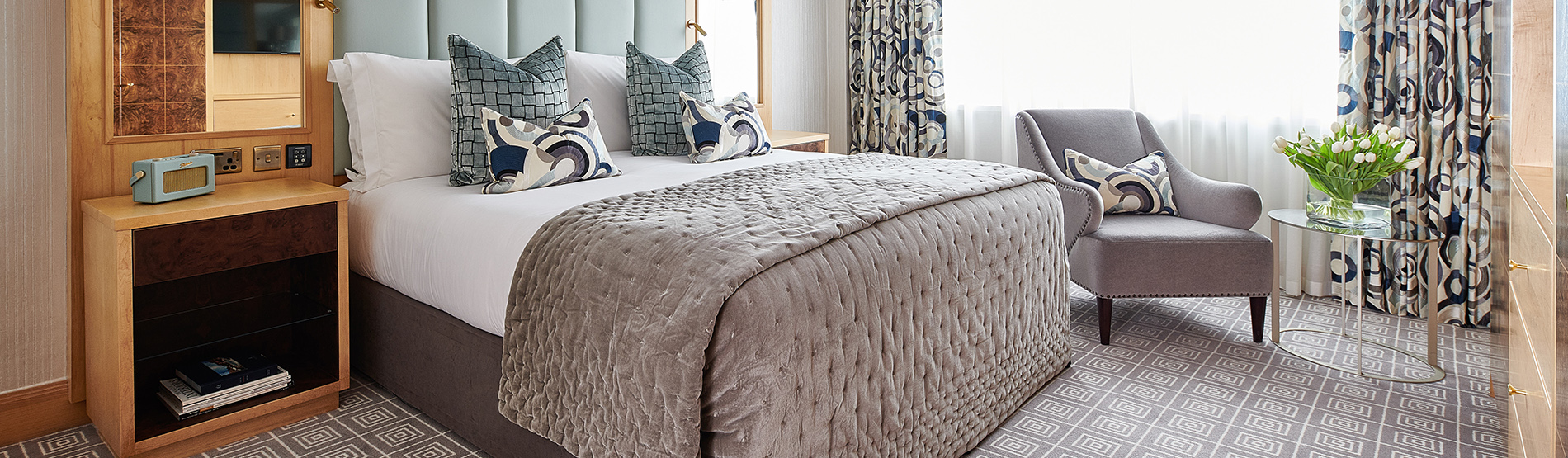 The bright and airy master bedroom of a luxury suite, showcasing a plush king bed and elegant contemporary decor at The Westbury.