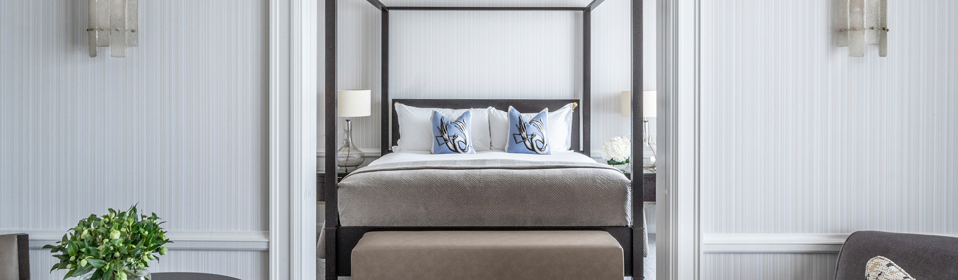 The Signature Suite at The Westbury Hotel, showcasing a luxurious four-poster bed visible through the open doorway of the living area.