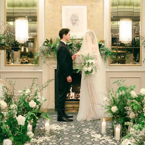 Bride and groom stand in front of a fireplace