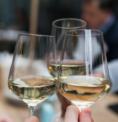 three glasses of white wine raising a toast
