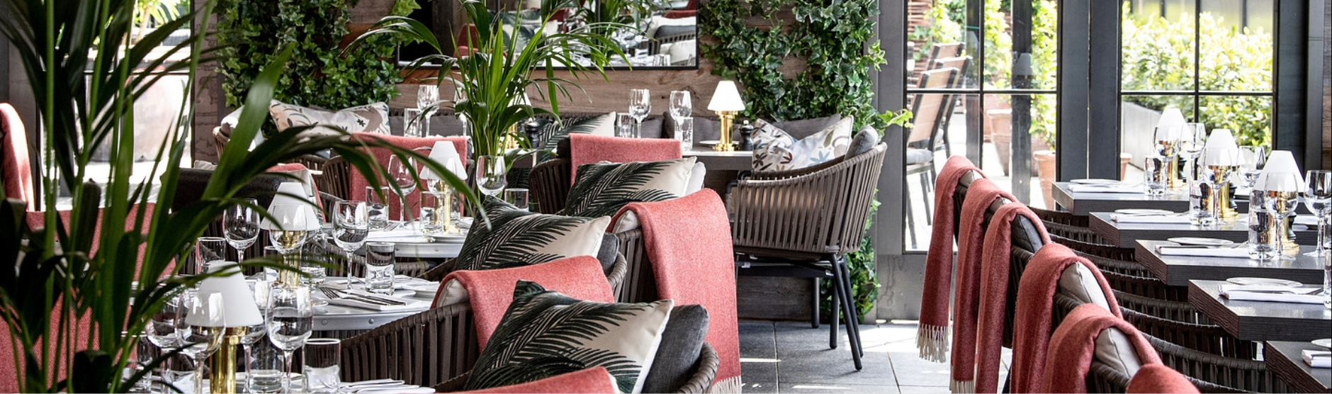 Set tables with wine glasses and red blankets on the terrace of The Hawthorn at The Croke Park hotel.